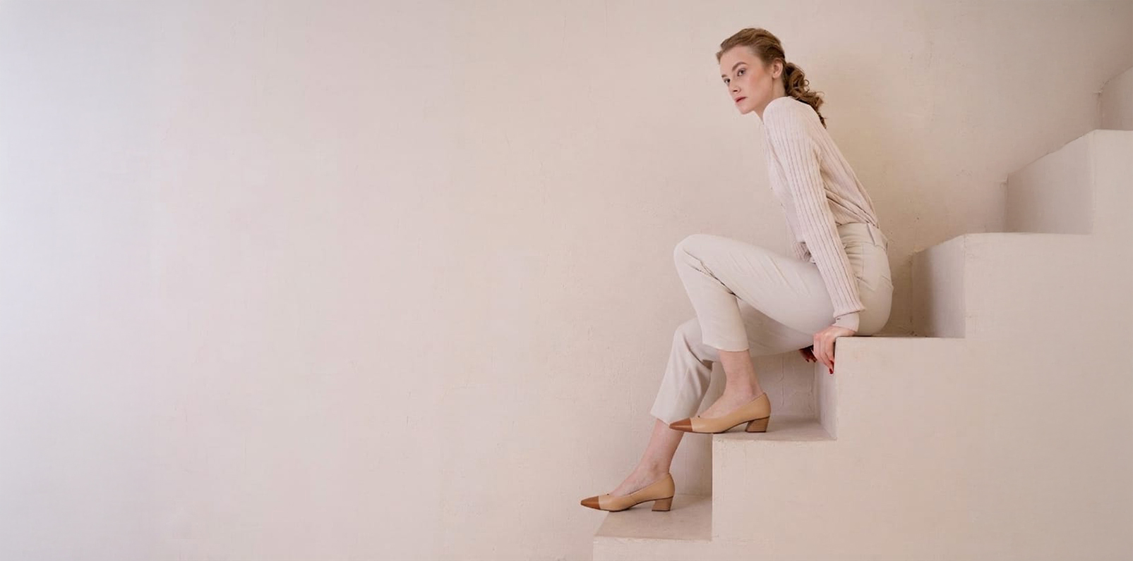 Woman wearing neutral two-tone pumps on sculptural steps